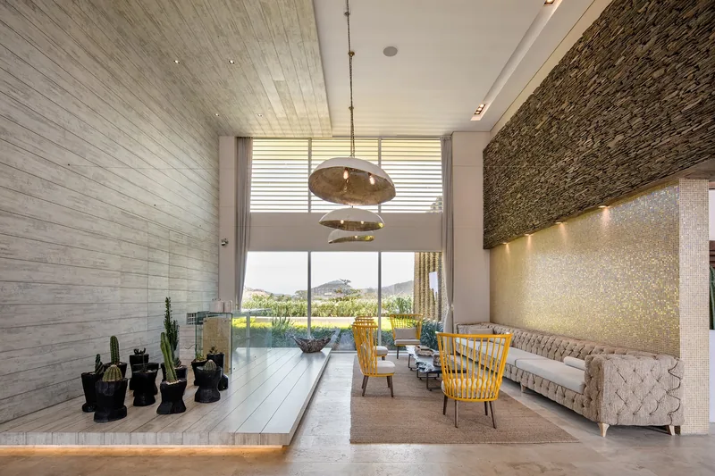 Salón social con muro de piedra y ventanal al jardín.